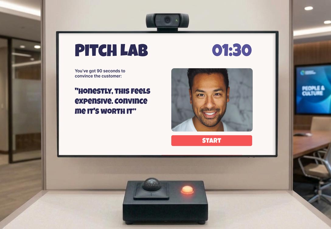 Pitch Lab station: a wall-mounted screen with camera, showing a 90-second objection-handling prompt and a start button, next to a physical trigger button on a stand.